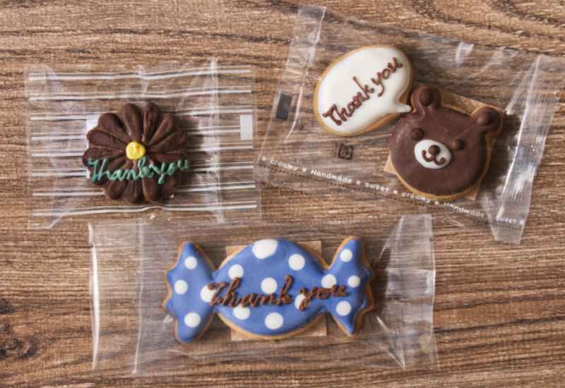 サンキュウのメッセージが書かれた花やくまちゃんやキャンディーの形のカラフルなアイシングクッキー